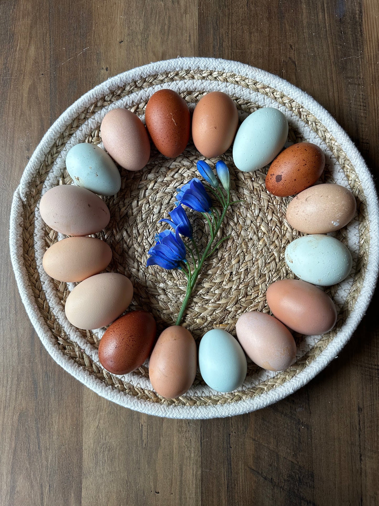 Assorted colored eggs in a woven basket on a wooden surface