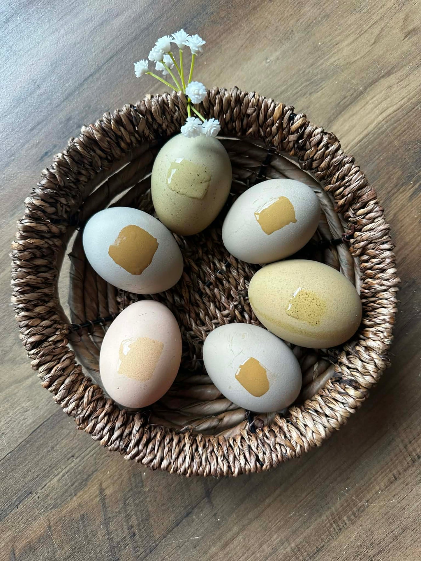Decorative eggs with gold accents in a woven basket on a wooden surface